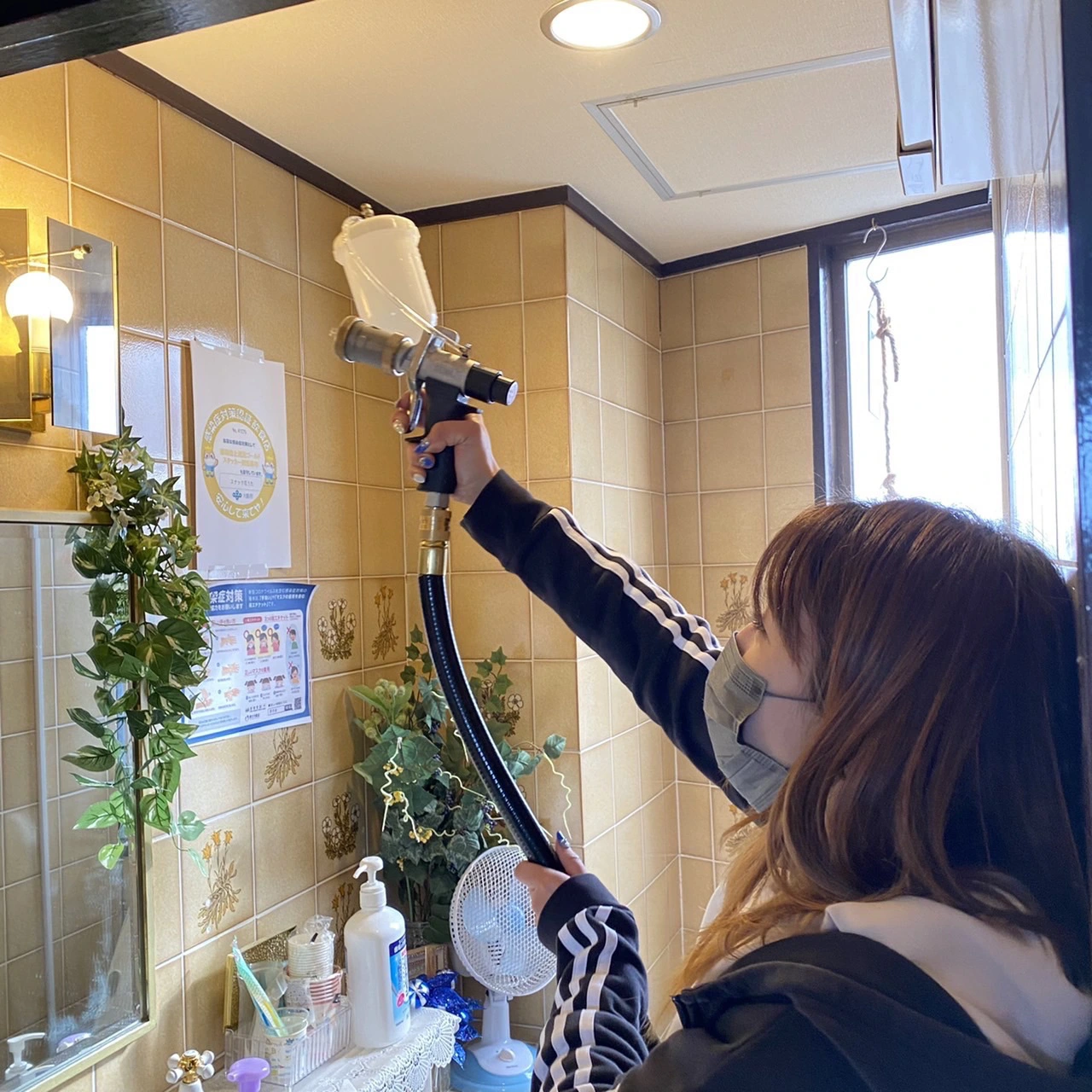 洗面台に光触媒コーティングを吹き付けている
